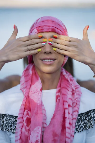 Woman with scarf pink and hands covering her eyes
