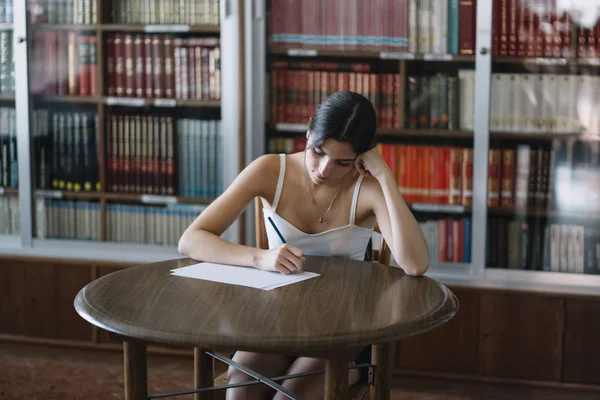 view of a young woman studying in the table on a library.