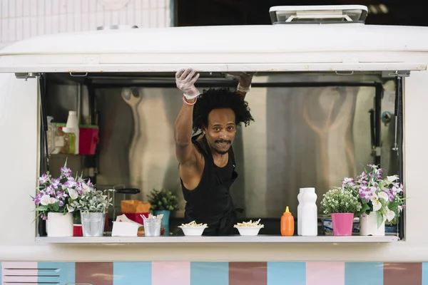 Smiling food vendor hands food to waiting customer