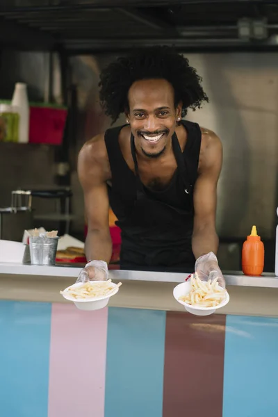 Smiling food vendor hands food to waiting customer