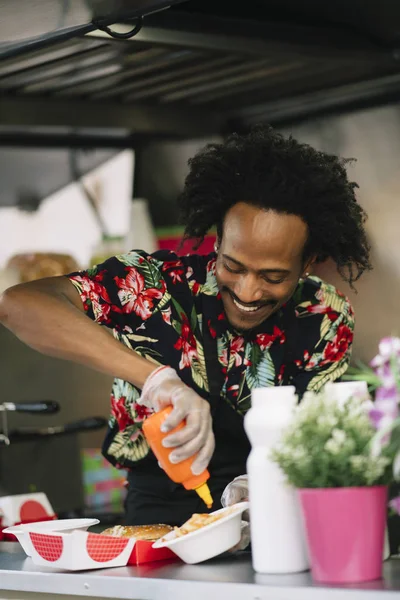 Smiling food vendor hands food to waiting customer