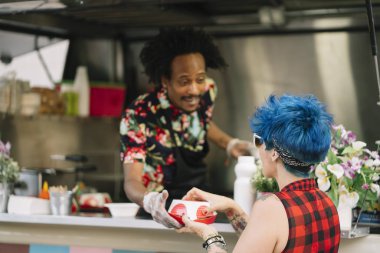 Gıda satıcı gülümseyen gıda bekleyen müşteriye eller