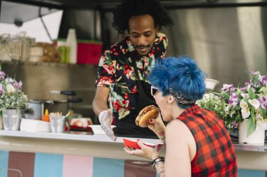 Gıda satıcı gülümseyen gıda bekleyen müşteriye eller