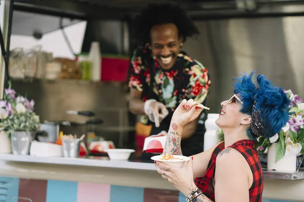 Smiling food vendor hands food to waiting customer