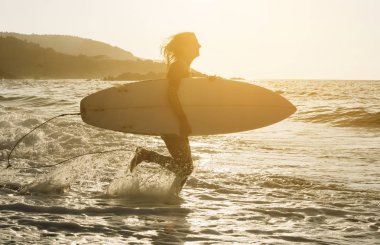Sörf tahtası ayakta okyanus, ıslak kum plajındaki kadınla.