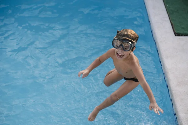 Kid playing and jumping in the pool