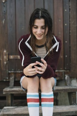 Genç kız ile smartphone ahşap evin yanındaki açık havada