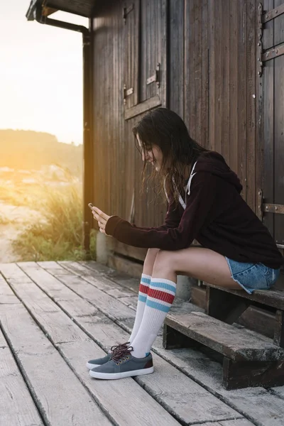 Młoda Dziewczyna Smartphone Zewnątrz Obok Dom Drewniany — Zdjęcie stockowe