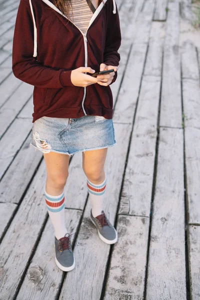 屋外木製の家の横にあるスマート フォンで若い女の子 — ストック写真