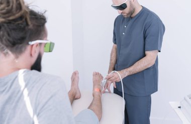 Yıldırım lazer için ekipman kullanan bir adam tedavi fizyoterapist