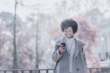 Cep telefonuyla sokakta çekici afro kadın portresi