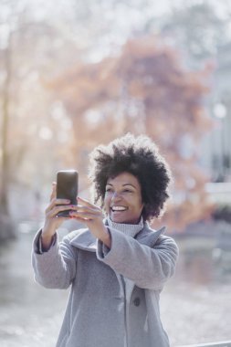 Cep telefonuyla sokakta çekici afro kadın portresi