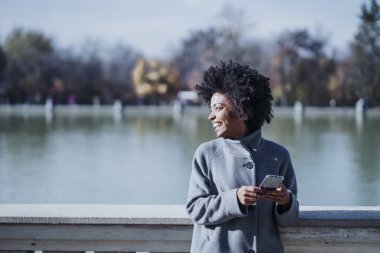 Cep telefonuyla sokakta çekici afro kadın portresi