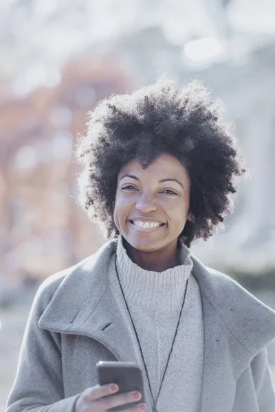Portrait of attractive afro woman using mobile phone in the street