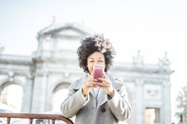 Madrid, İspanya cep telefonuyla çekici afro kadın portresi. Puerta de Alcala.