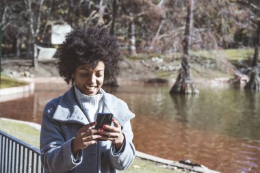 Cep telefonuyla sokakta çekici afro kadın portresi