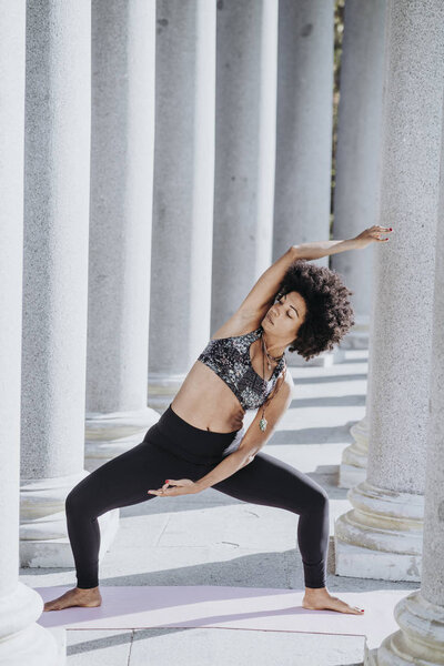 Афроженщина, практикующая йогу в городе
