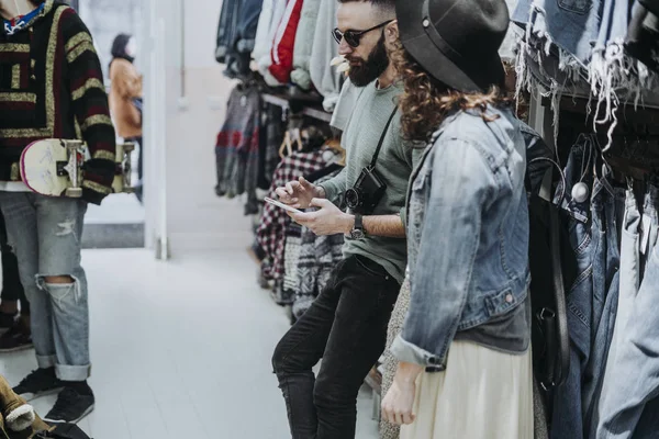 Two friends with smartphone at the fashion shop