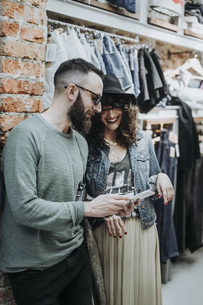 Two friends with smartphone at the fashion shop