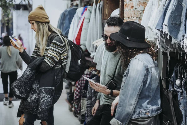 Two friends with smartphone at the fashion shop