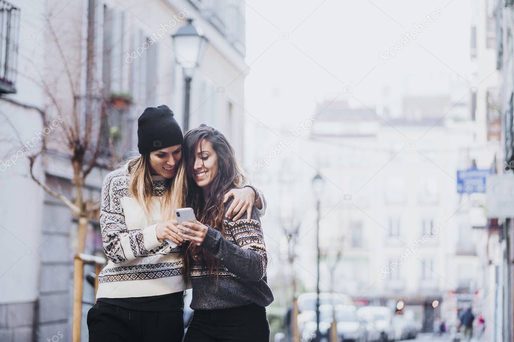 Two women with smartphone in the street