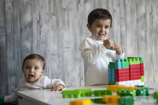 Two happy baby playing with toy blocks.
