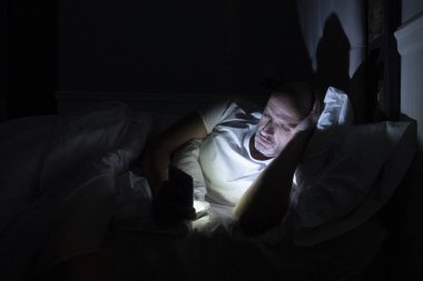 Adam uyumak yerine telefonunu kullanıyor. Teknoloji bağımlılığı.