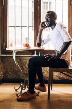 Bir kahve yaparken cep telefonu Afrika adam danışır.