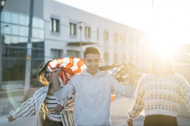 Sokaklarda Amerikan bayrağı taşıyan bir grup mutlu arkadaş.