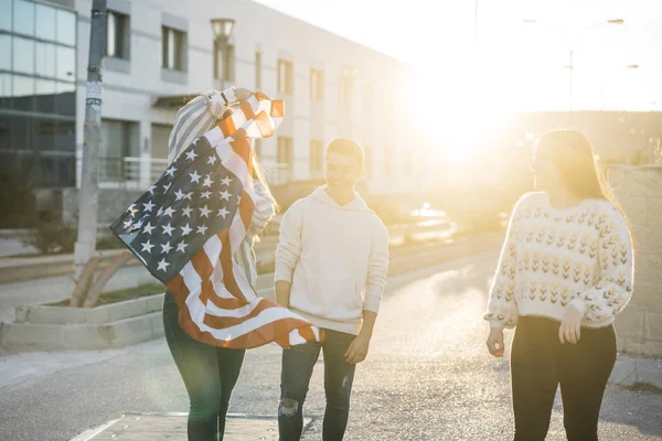 Sokaklarda Amerikan bayrağı taşıyan bir grup mutlu arkadaş.
