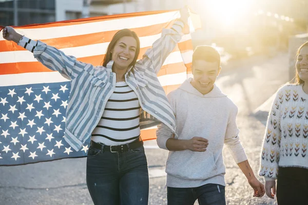 Sokaklarda Amerikan bayrağı taşıyan bir grup mutlu arkadaş.