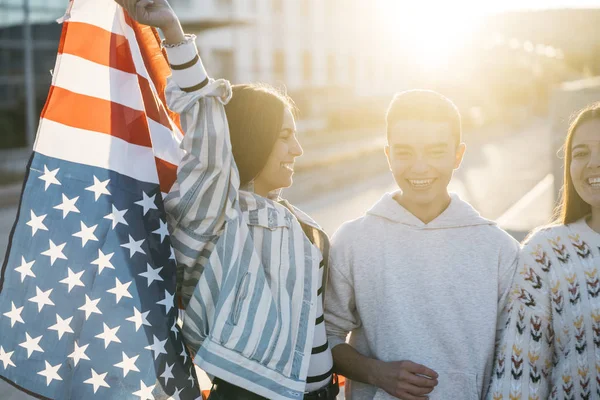 Sokaklarda Amerikan bayrağı taşıyan bir grup mutlu arkadaş.