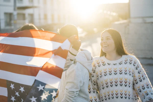 Sokaklarda Amerikan bayrağı taşıyan bir grup mutlu arkadaş.
