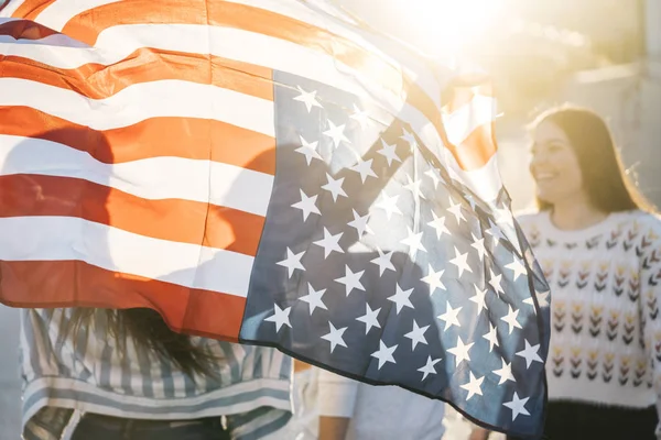 Sokaklarda Amerikan bayrağı taşıyan bir grup mutlu arkadaş.