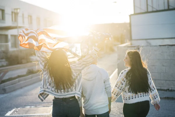 Sokaklarda Amerikan bayrağı taşıyan bir grup mutlu arkadaş.