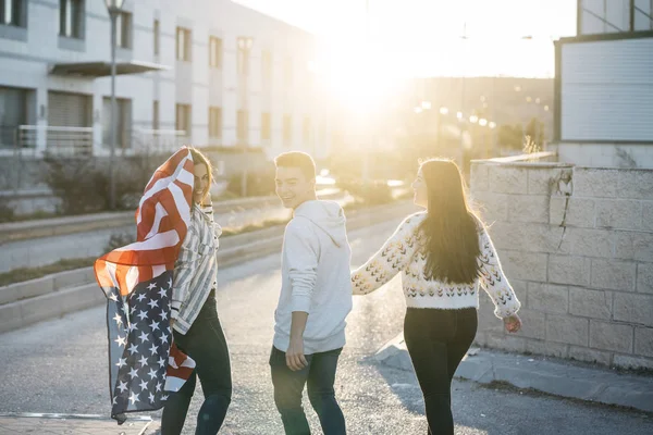 Sokaklarda Amerikan bayrağı taşıyan bir grup mutlu arkadaş.