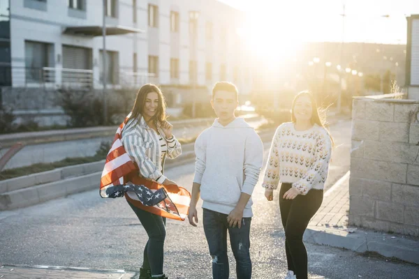 Sokaklarda Amerikan bayrağı taşıyan bir grup mutlu arkadaş.