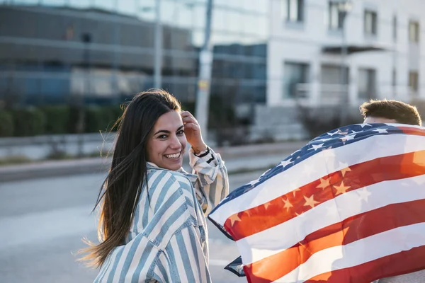 Sokaklarda Amerikan bayrağı taşıyan bir grup mutlu arkadaş.