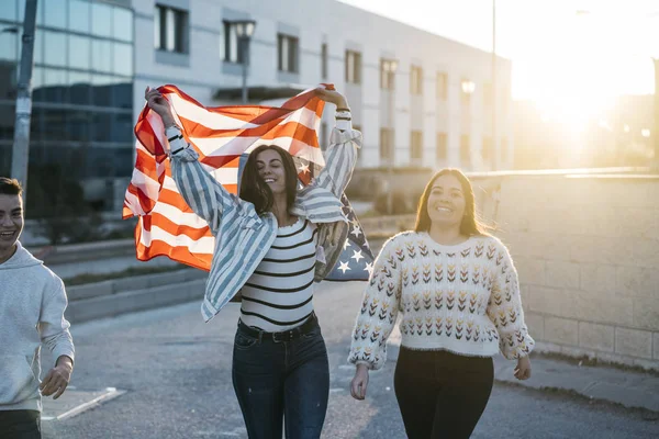 Sokaklarda Amerikan bayrağı taşıyan bir grup mutlu arkadaş.
