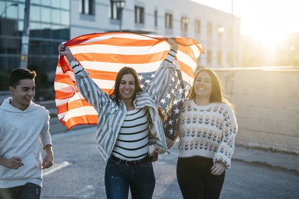 Sokaklarda Amerikan bayrağı taşıyan bir grup mutlu arkadaş.