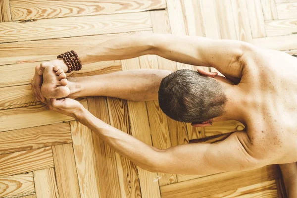 Een man die doen yoga op de houten vloer — Stockfoto