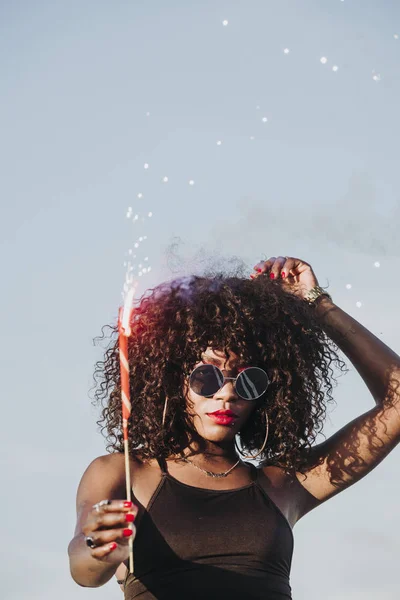 Young afro woman with sparklers and sunglasses — Stock Photo, Image