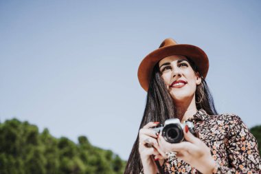 Fotoğraf çekmek için kamera kullanan gülümseyen genç bir kadın..