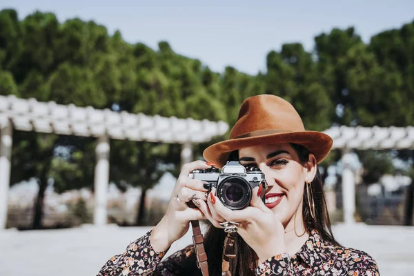 Leende ung kvinna använder en kamera för att ta ett foto. — Stockfoto