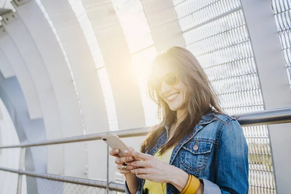 Donna felice che cammina per strada controllando il contenuto dello smartphone — Foto Stock