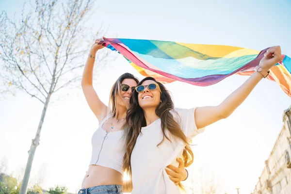 Casal lésbicas mulher com gay orgulho bandeira no o rua — Fotografia de Stock