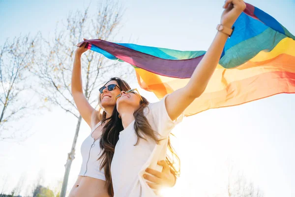 Pasangan wanita lesbian dengan bendera kebanggaan gay di jalan — Stok Foto