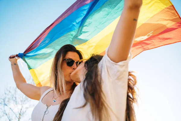 Pár lesbických žen s vlajkou homosexuální pýchy na ulici — Stock fotografie