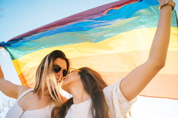 Pareja lesbiana con bandera de orgullo gay en la calle — Foto de Stock