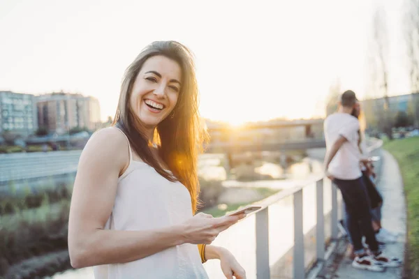 Mujer feliz mensajes de texto en el teléfono inteligente en la calle — Foto de Stock